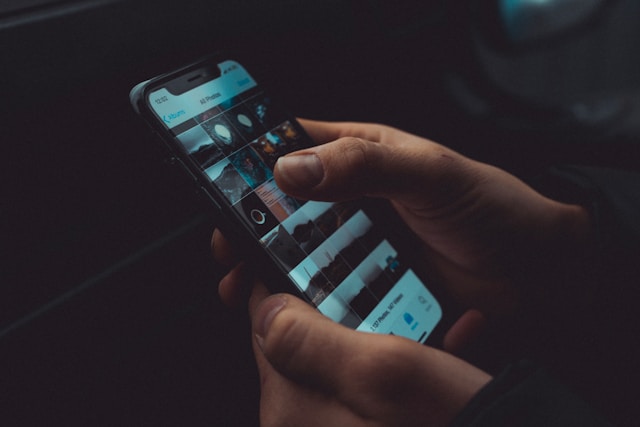 Hand holding phone social media dark background
